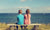 boy and girl sitting on a bench looking at the sea