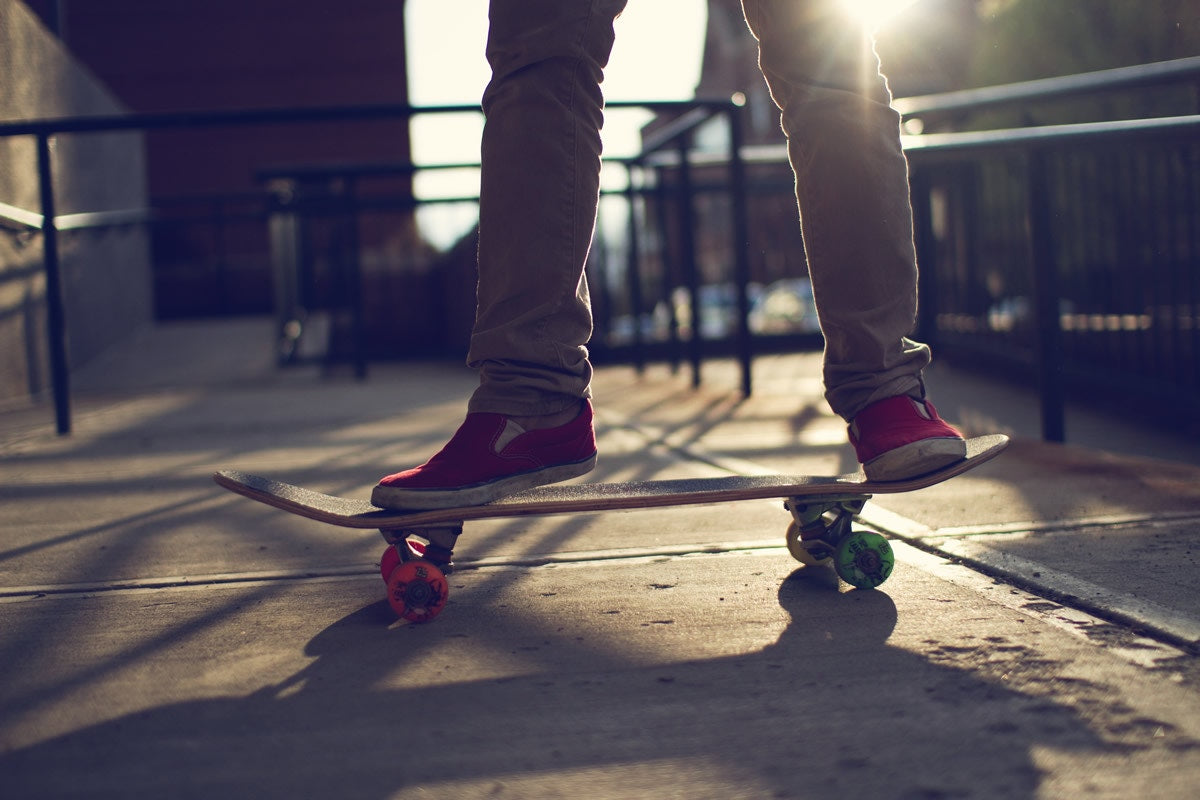 legs on a skateboard with red shoes