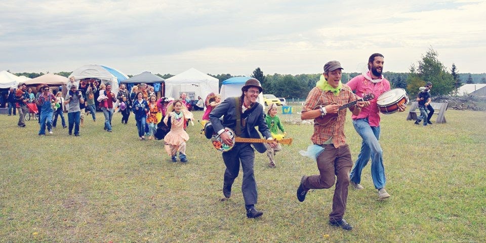 kids and adults following a band outside with a guitar and drums