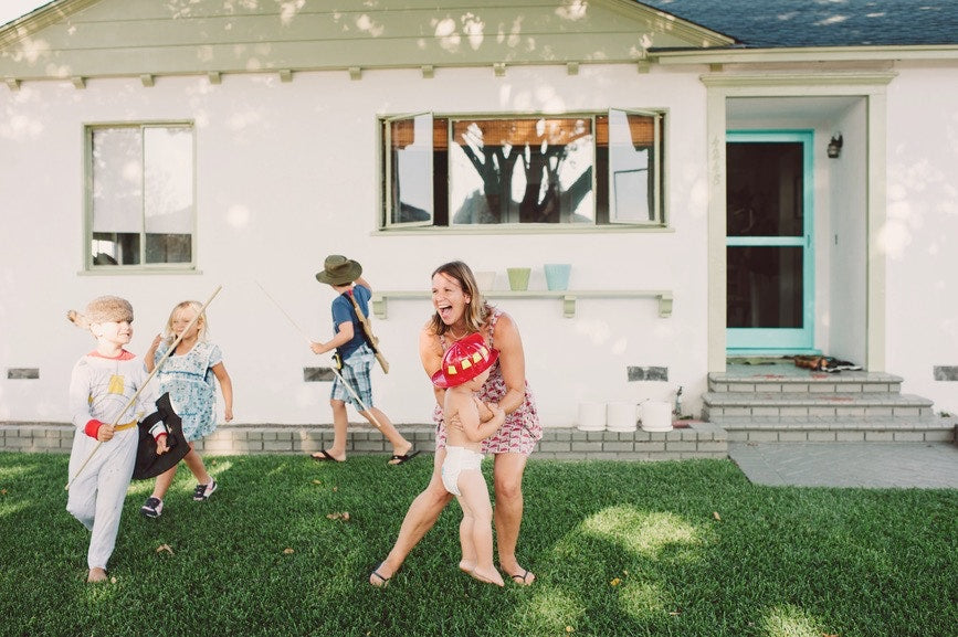 mom playing with four kids outside her house kids have costumes on