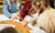 four kids around a table with pens and paper