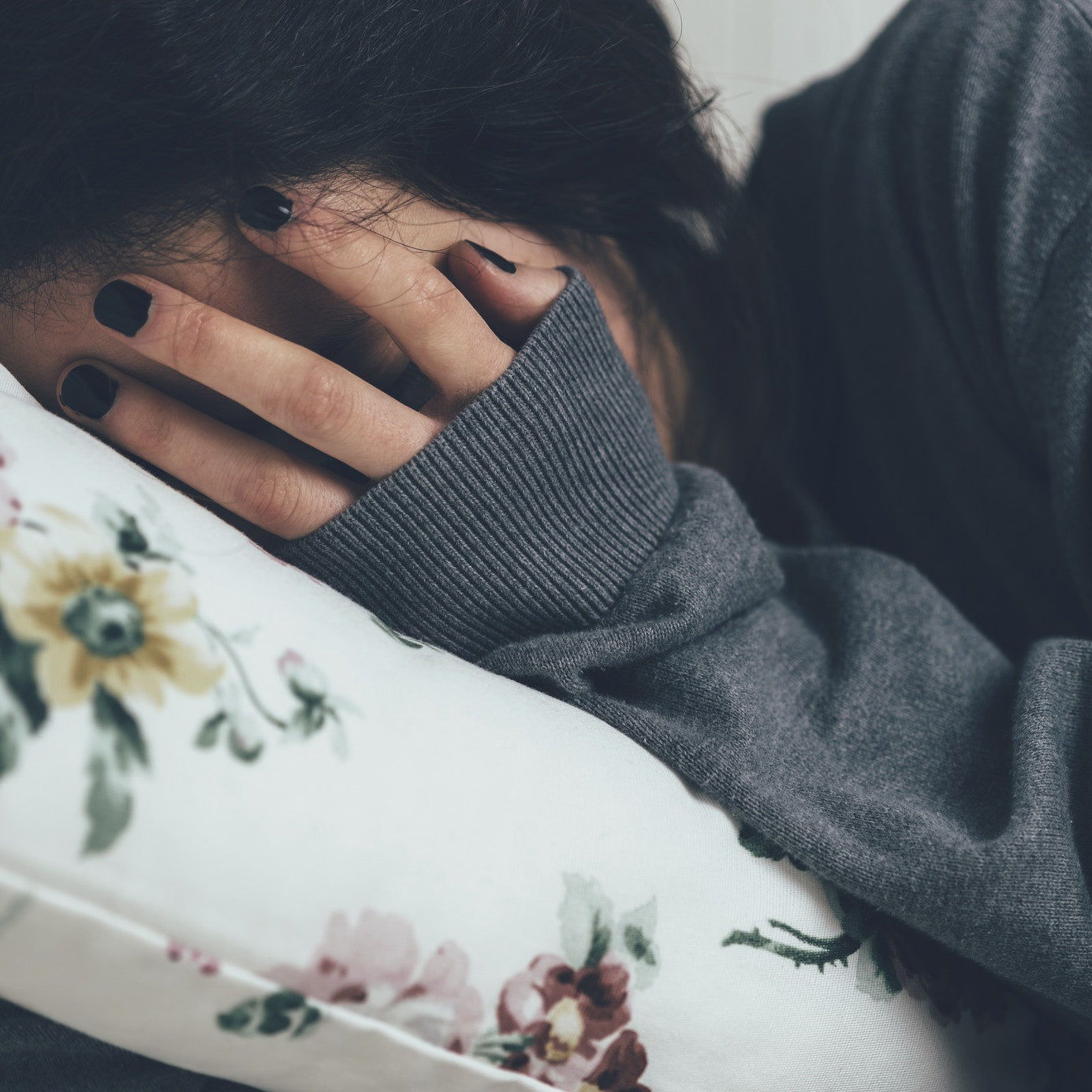 women covering face with hands and sleeping on bed