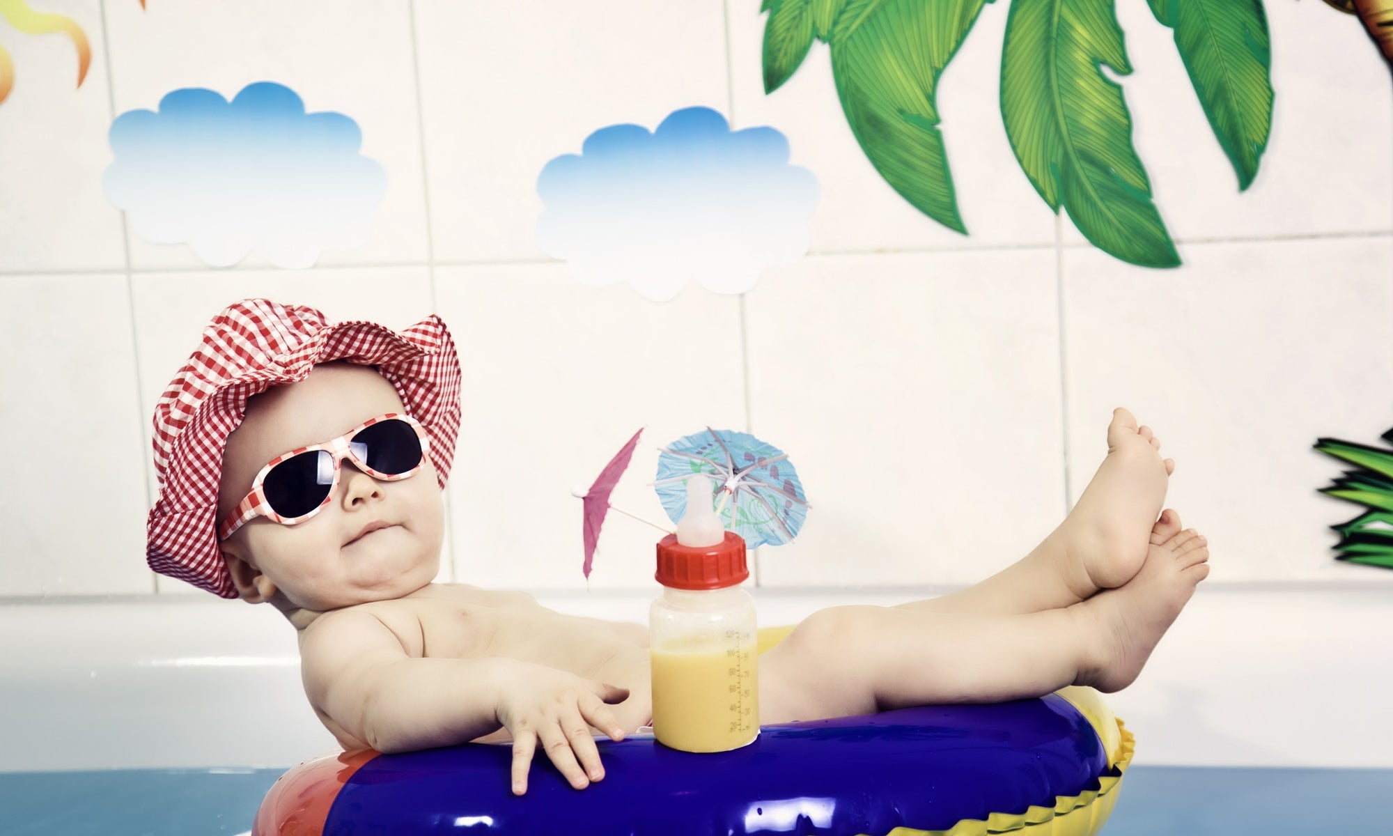 baby boy wearing sunglasses and hat on a tiny inflatable swim ring