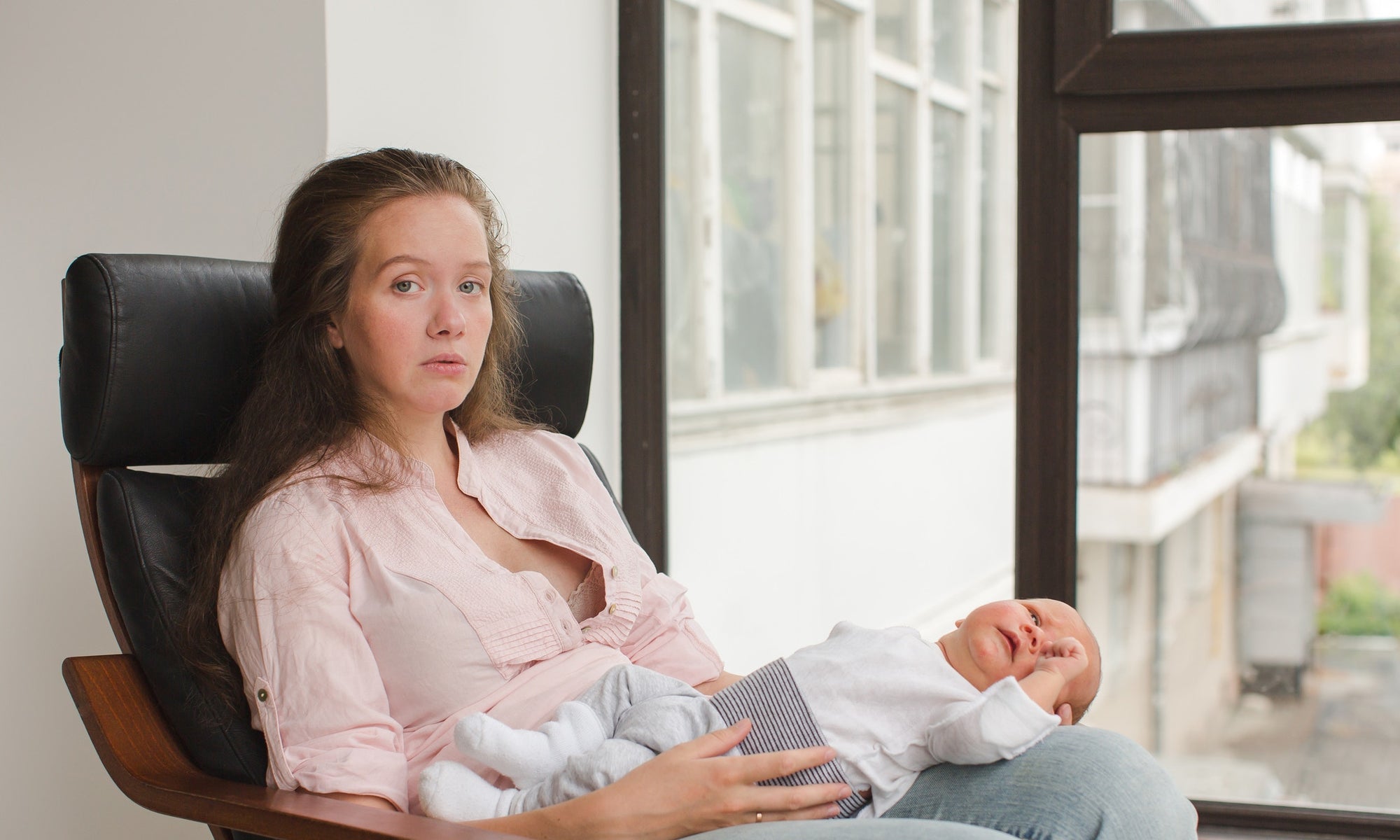 Depressed mother holding new born baby and sitting on a chair