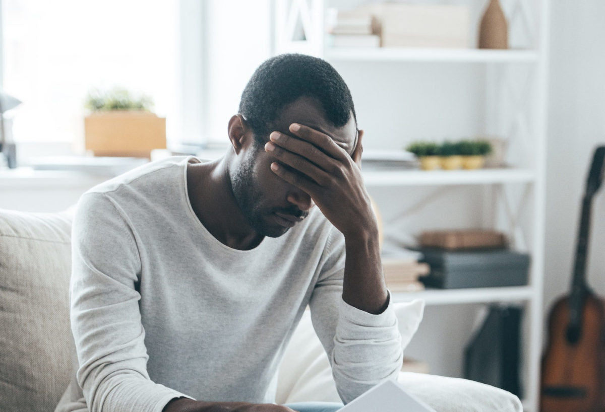 A guy is feeling depressed by holding his hand on forehead