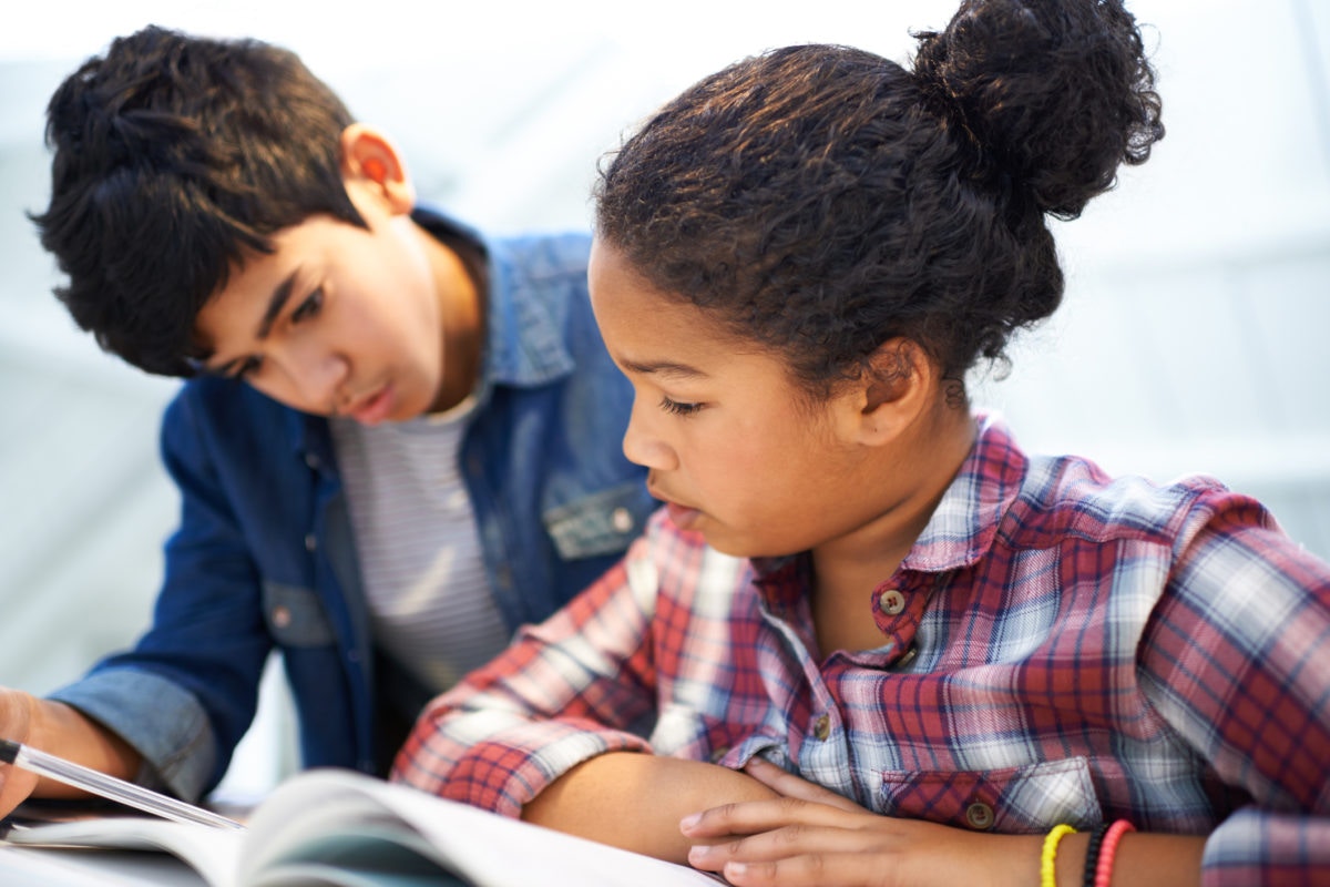 Two children are reading books in a school