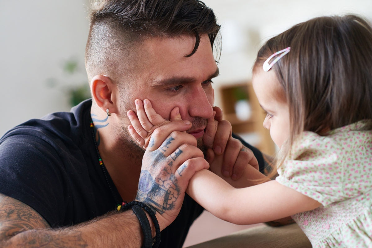 little girl cupping her fathers face