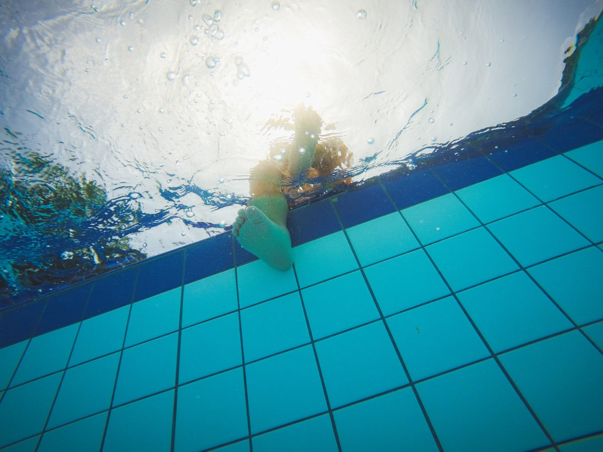 kid dipping his feet into a swimming pool