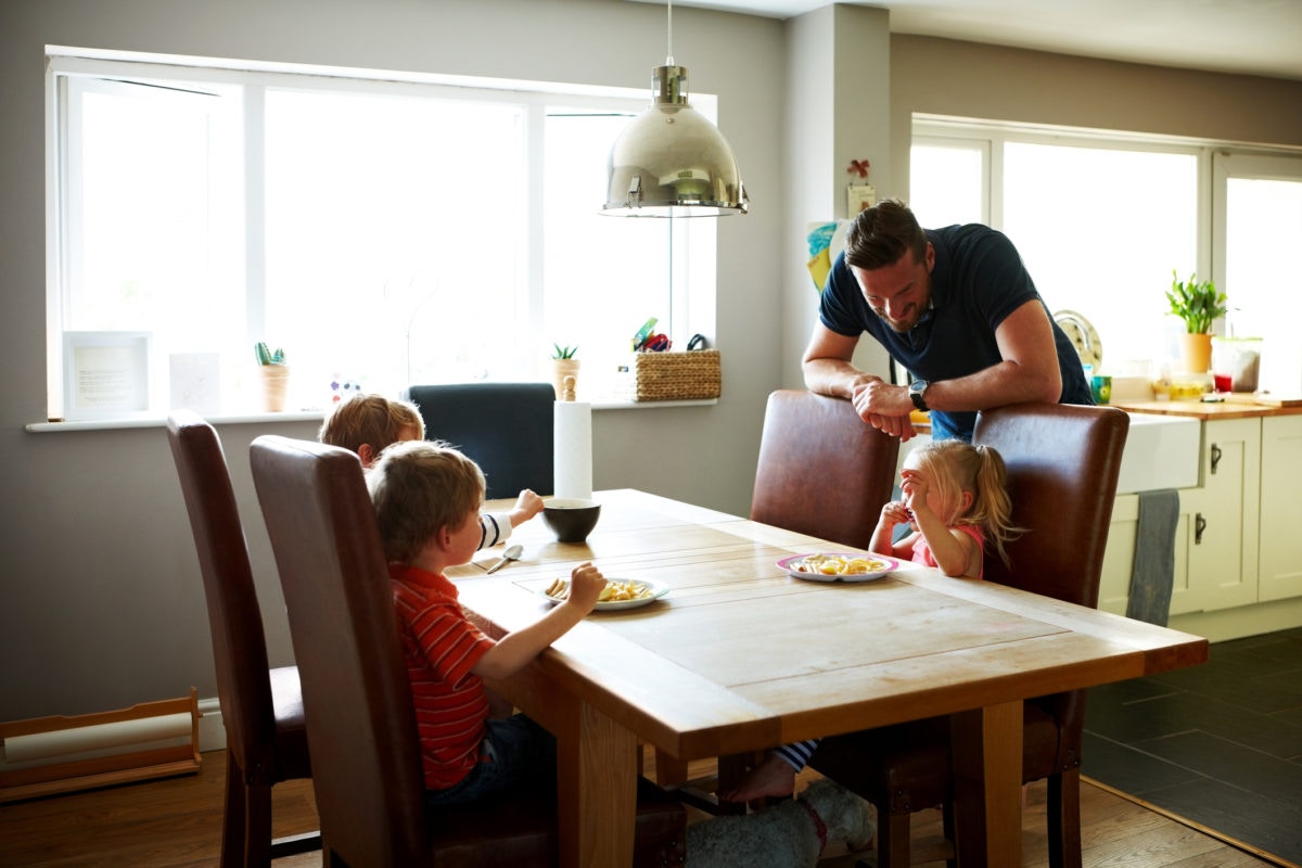 three little children sitting at dinning table and having a snack of biscuit