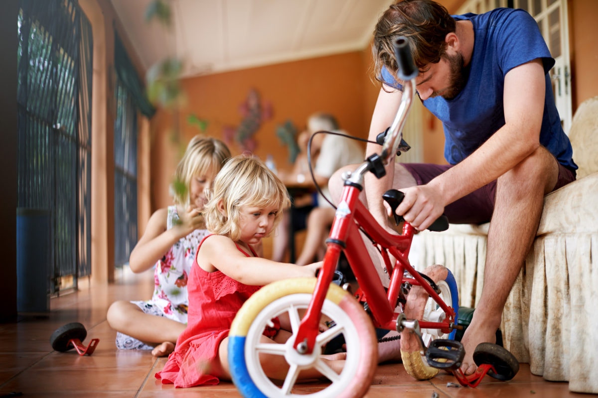 Father repairing bycycle with his daughters