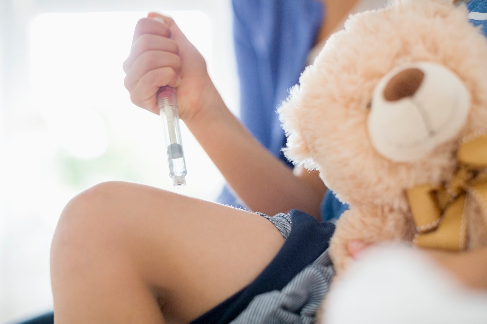 girl hand holding syringe and teddy bear