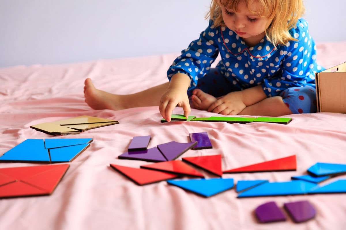 cute little girl playing puzzle on bed