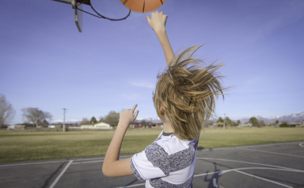 little boy throwing ball to basket