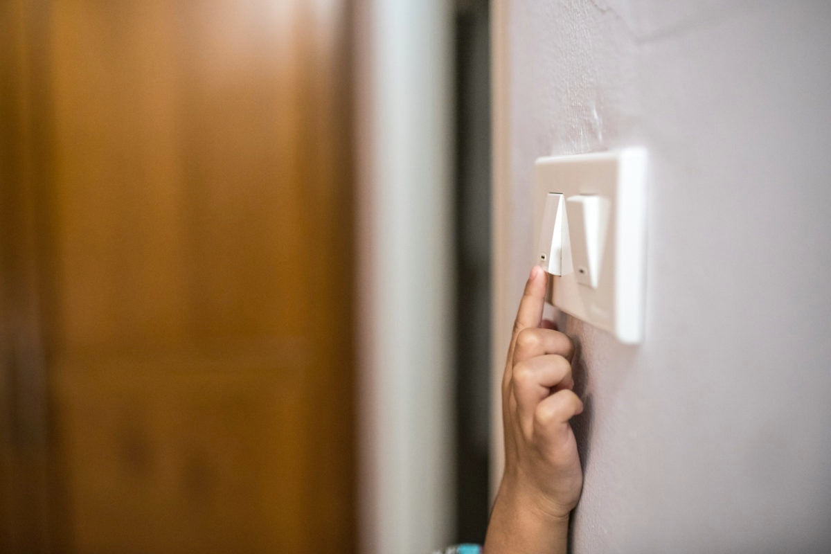 baby hand touching a panel with two light switches