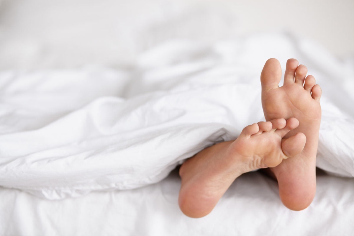 Sleeping woman feet under blanket