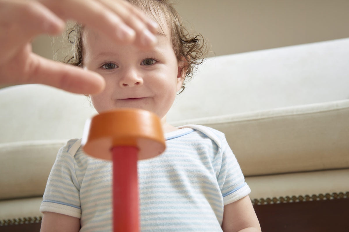 kid looking at a wooden toy