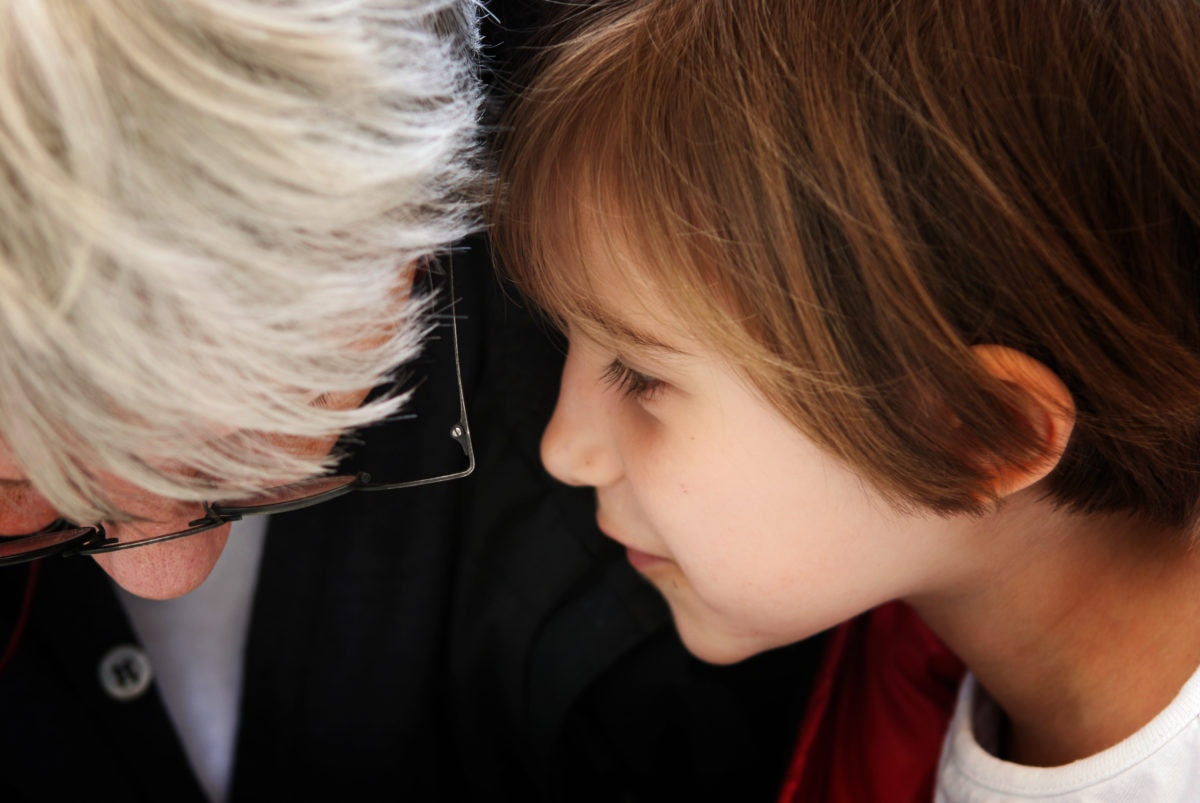 boy saying something into the ear of an adult