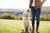 Girl is standing in a open field holding a dog