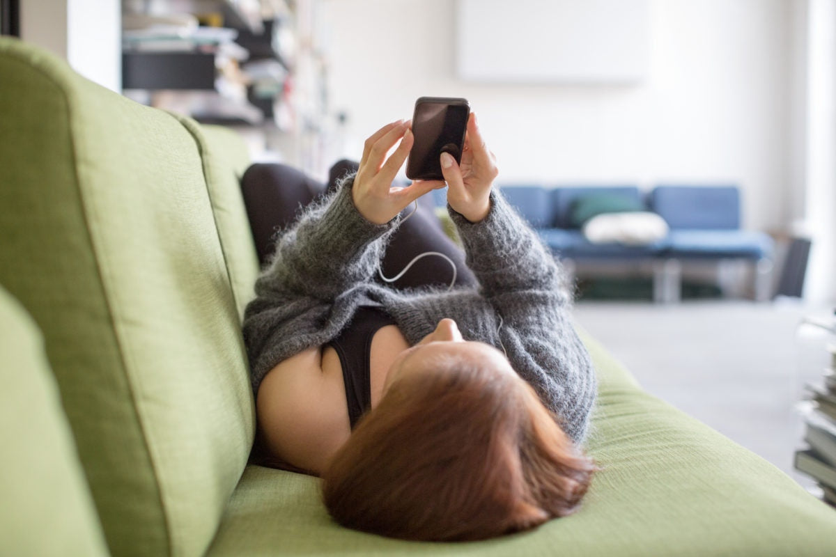 Girl listening to music lying on sofa