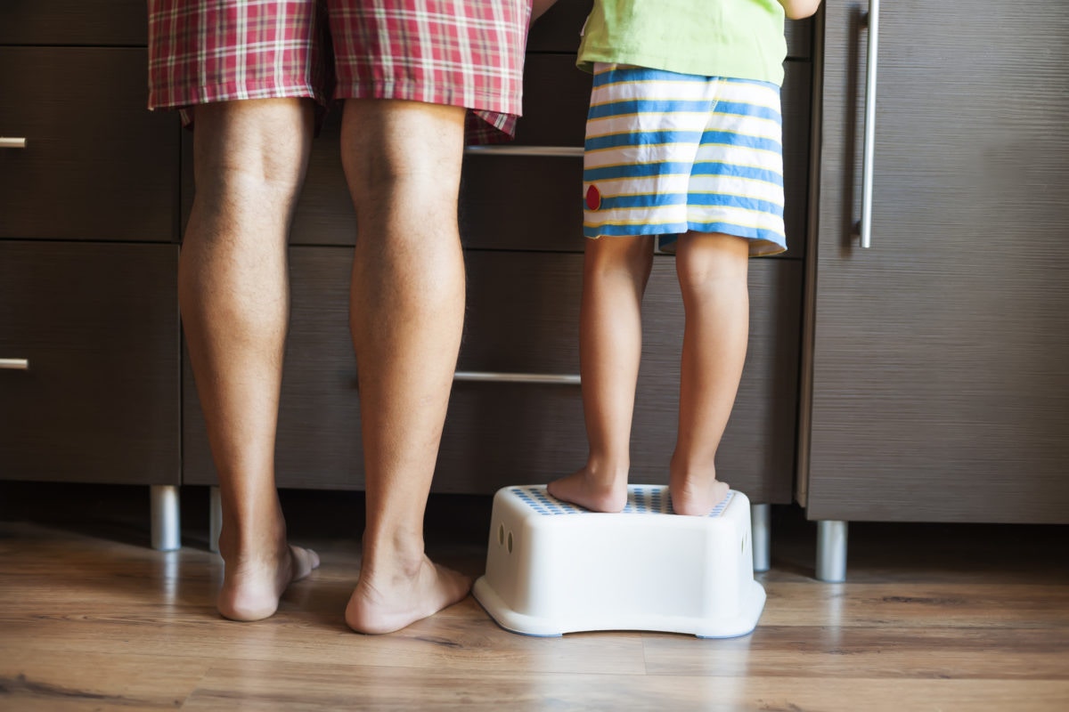 Child standing on a pedistal for using the basin with father