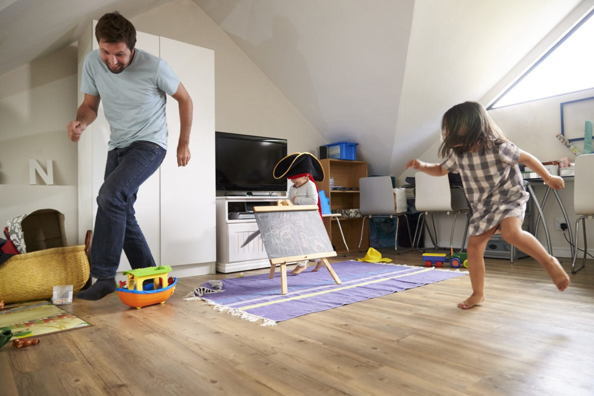 Little girl catching father, having fun with dad at home