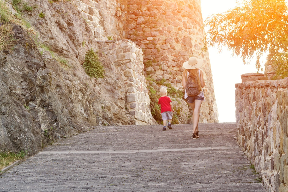 girl in a hat with a young son walking near the walls of the fortress