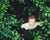 little boy standing in forest looking up