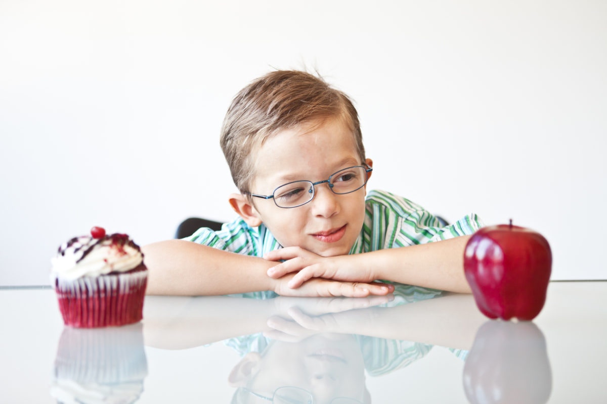 little Boy Choosing Between A Apple and Cupcake