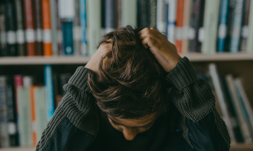 a boy wearing long sleeves sweater looking down and pulling hair