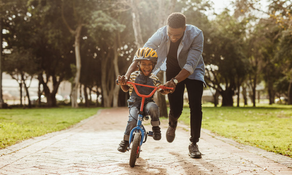 father teaching his son cycling at park