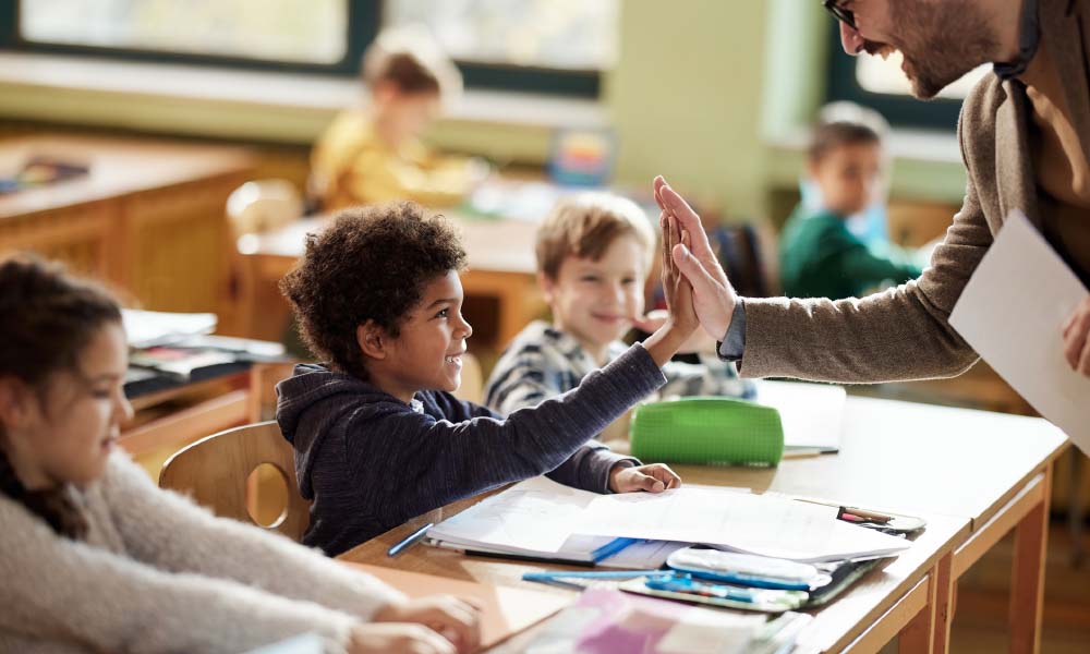 teacher and schoolboy giving each other high-five