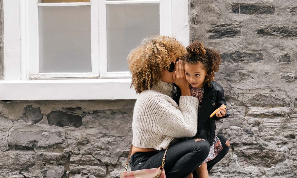 woman whispering in child's ear