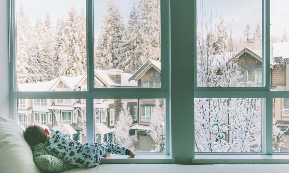 little baby boy lying near window and looking outside on snow